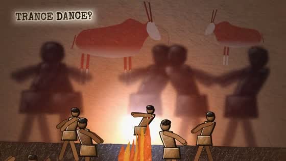 Film still: dancers by firelight with rock paintings behind them